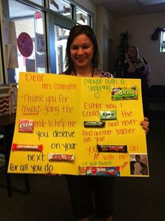 a woman holding up a sign with candy bars on it