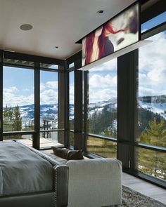 a bedroom with large windows and a view of the mountains in the backround