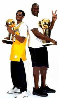 two men holding trophies and posing for the camera