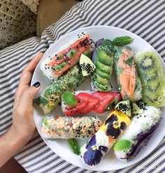 a white plate topped with different types of sushi on top of a striped table cloth