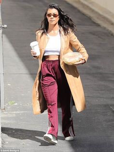 the woman is walking down the street with her coffee and donut in hand,