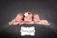 three newborn babies are sleeping together on a gray blanket with their heads resting on each other