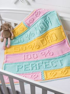 a crocheted blanket on top of a bed next to a teddy bear and stuffed animal