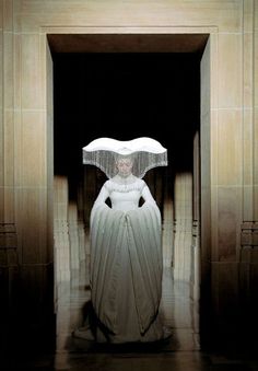 a woman in a white gown with an umbrella over her head is standing in a doorway