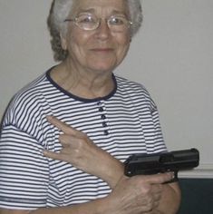 an older woman holding a cell phone in her right hand and pointing at the camera