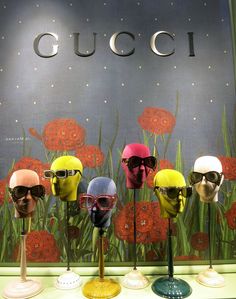 gucci sunglasses are displayed on display in front of a wall with red flowers