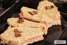 two sandwiches with writing on them sitting on top of a black plate next to other food items