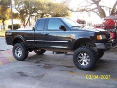 a black truck parked on the side of a road next to a red fire hydrant