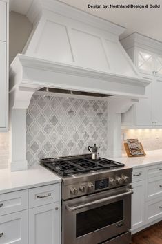 a stove top oven sitting inside of a kitchen next to white cabinets and counter tops