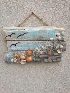 a wooden sign with seashells and seagulls hanging from it's side