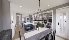 a large open concept kitchen and dining room with white walls, wood flooring and gray cabinets