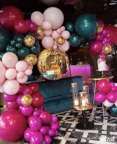 a room filled with lots of balloons and tables covered in gold, pink, and green