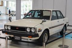 an old white car is on display in a building