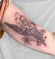 a woman's arm with flowers on it and a bird sitting on top of the branch