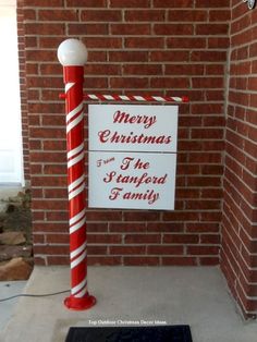 a red and white pole with a merry christmas sign on it next to a brick wall