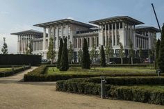 two large buildings sitting next to each other on top of a lush green park covered in trees