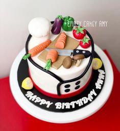 a birthday cake with vegetables on it sitting on top of a red tableclothed surface