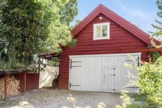 a red barn with a white door and window on the outside, surrounded by trees