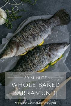 two whole baked fish sitting on top of parchment paper