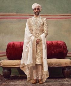 a man in a white outfit standing next to a red couch