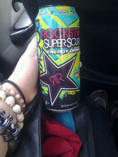 a can of rock star energy drink sitting in the back seat of a car next to a woman's hand