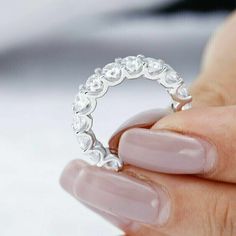 a close up of a person holding a ring with diamonds on it's fingers