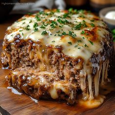 a meatloaf covered in cheese and sauce on top of a wooden cutting board