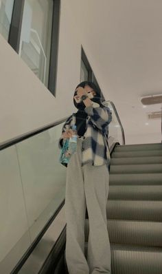 a man standing on an escalator with his hand in his mouth and holding a water bottle