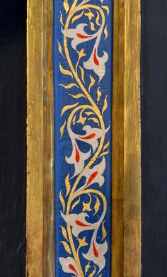 an ornate blue and gold painting on the side of a black wall with yellow trim