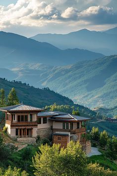 a large house sitting on the side of a lush green hillside next to a forest