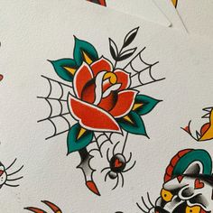 several different tattoos on white paper with red and green flowers, spider webs, and cats