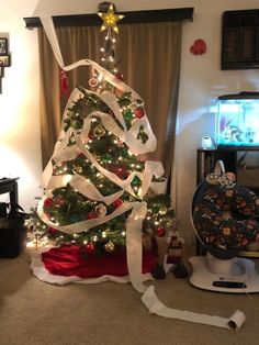 a christmas tree is decorated with white ribbon