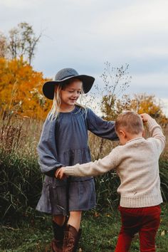 two young children playing with each other in the grass