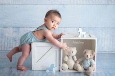 a baby sitting in front of a box with two teddy bears