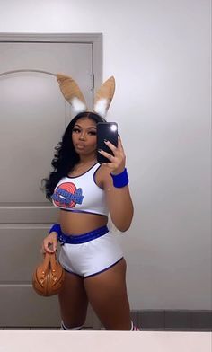 a woman in bunny ears taking a selfie with her cell phone and holding a purse