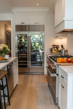 an open kitchen with stainless steel appliances and white cabinets, along with wood flooring