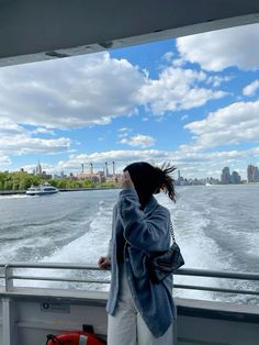 a woman standing on the back of a boat looking out at the water and buildings