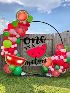 a one in a melon balloon arch with watermelon slices and balloons on it