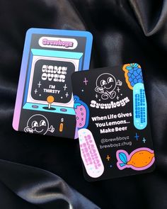 two cards with stickers on them sitting next to each other in front of a black background