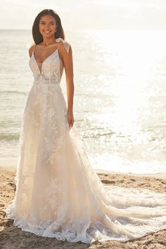 a woman standing on top of a beach next to the ocean wearing a wedding dress