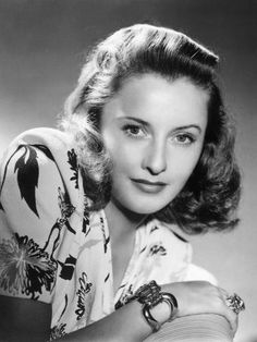 an old black and white photo of a woman with her hands on her chest, leaning against the wall