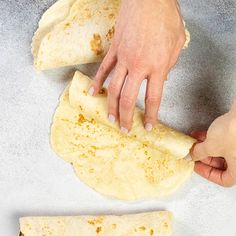 someone is making tortilla bread on a table with one hand reaching for it