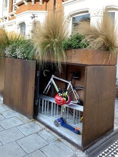 a bike is parked in a planter on the side of a building with plants growing out of it