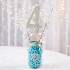 a glass jar filled with candy and snowflakes on top of a white table