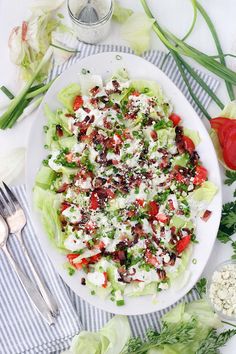 a white plate topped with lettuce, tomatoes and feta cheese covered in dressing