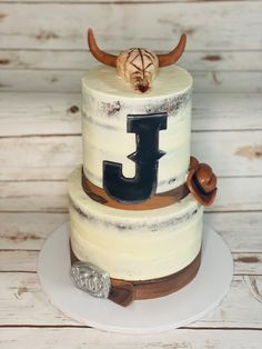 a three tiered cake with the letter j on it's side and an antelope topper