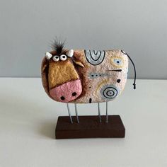 a cow made out of fabric sitting on top of a wooden stand with two eyes