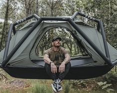 a man sitting in a hammock with his legs crossed and hands on the ground