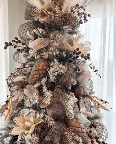 a christmas tree decorated with pine cones, feathers and other decorations is shown in front of a window