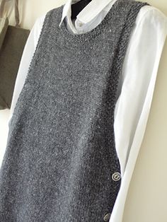 a gray sweater vest sitting on top of a white shirt